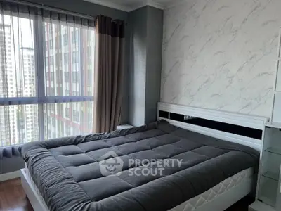 Modern bedroom with large window and stylish decor in high-rise apartment.