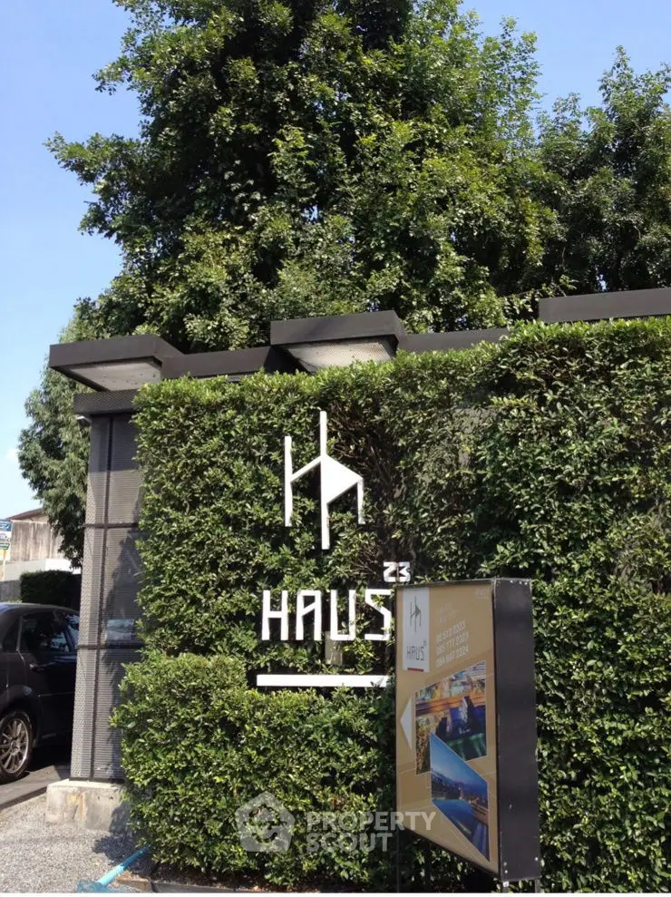Modern building entrance with lush greenery and stylish signage