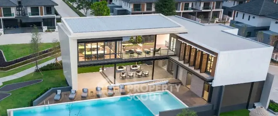Luxurious modern villa with expansive pool and outdoor seating, showcasing contemporary architecture and lush surroundings.