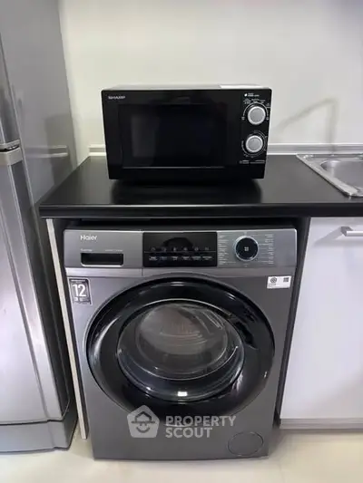 Modern kitchen with washing machine and microwave setup