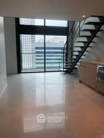 Modern loft with large windows and sleek staircase in urban high-rise.