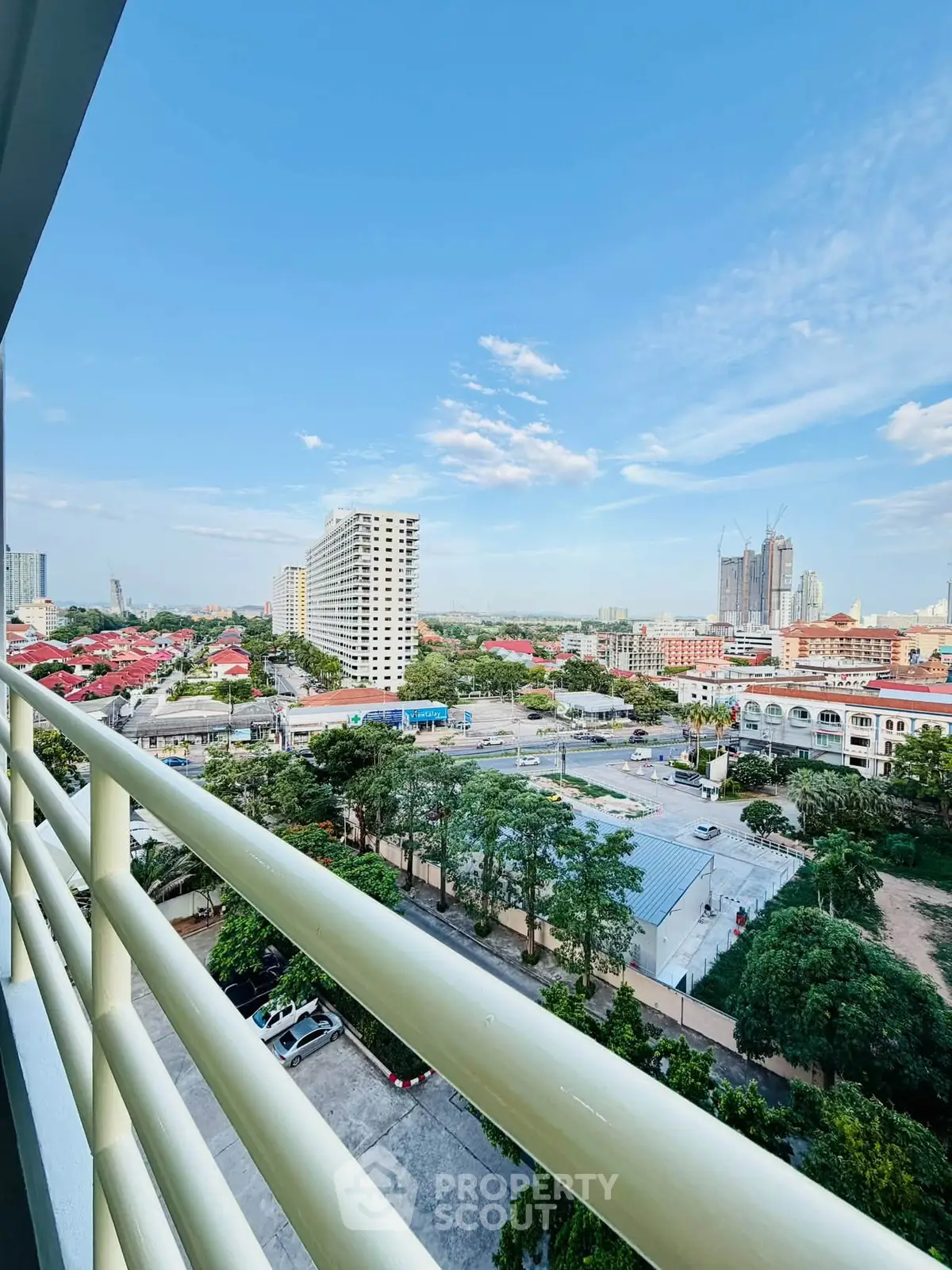 Stunning cityscape view from a high-rise balcony overlooking urban skyline and lush greenery.
