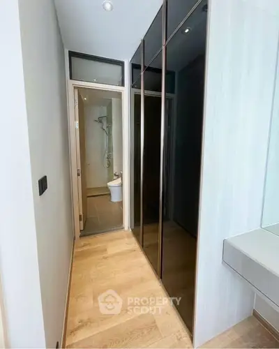 Modern apartment hallway with sleek mirrored closet and bathroom view