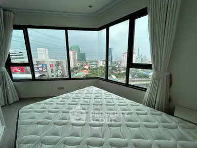 Spacious bedroom with panoramic city view and large windows in modern apartment.