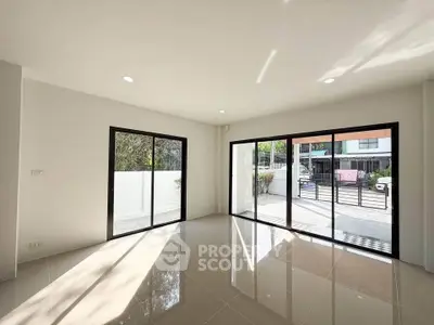 Spacious modern living room with large windows and glossy tiled floors, offering abundant natural light.
