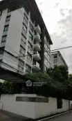 Modern multi-story residential building with lush greenery and balconies.