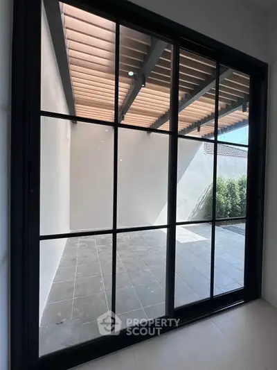 Modern patio with large sliding glass doors and tiled flooring, perfect for outdoor relaxation.