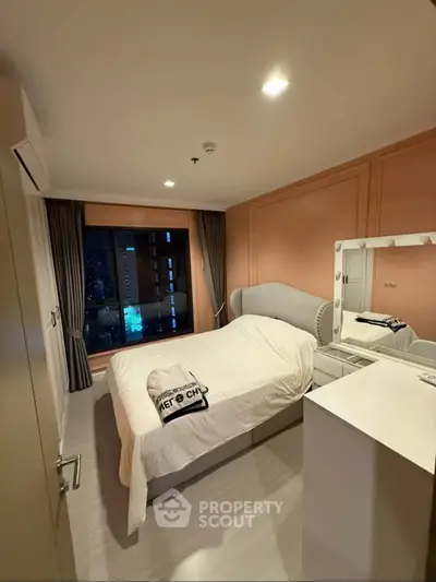 Cozy bedroom with city view, featuring elegant decor and ample natural light.