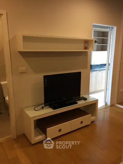 Modern living room with sleek TV stand and open kitchen view, perfect for contemporary living.