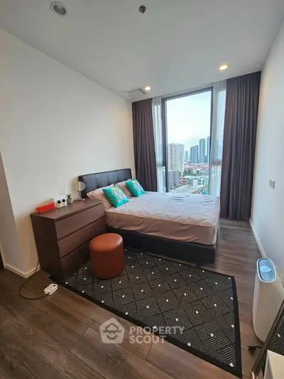Modern bedroom with city view, featuring stylish decor and large windows for natural light.