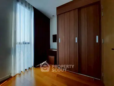 Elegant bedroom with wooden floors and large closet in modern apartment.