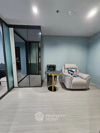 Modern living room with sleek glass partition and cozy recliner chair.