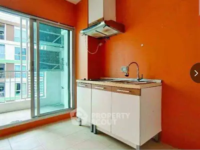 Modern kitchen with vibrant orange walls and balcony access