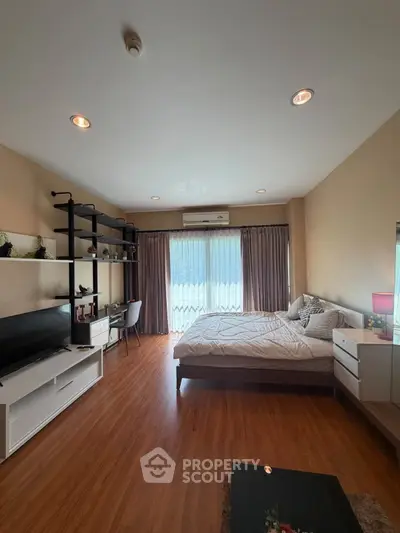 Spacious bedroom with modern decor and large window offering natural light
