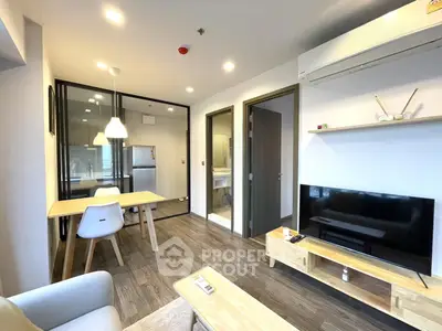 Modern living room with open kitchen, featuring sleek furniture and bright lighting.