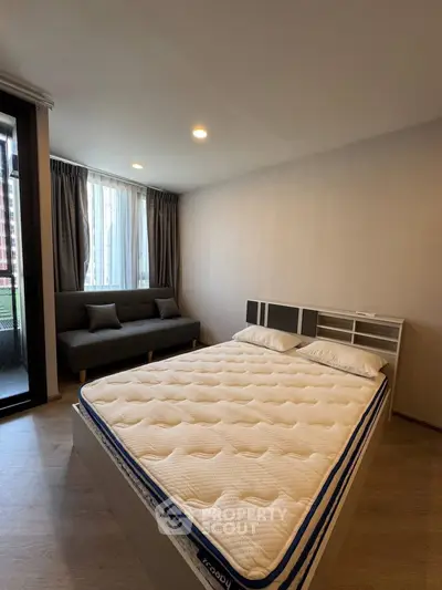 Spacious bedroom with modern decor and large window offering natural light.