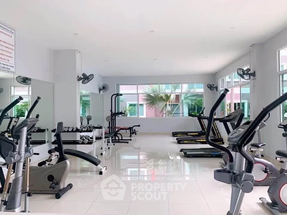 Spacious modern gym with state-of-the-art fitness equipment and large windows for natural light.