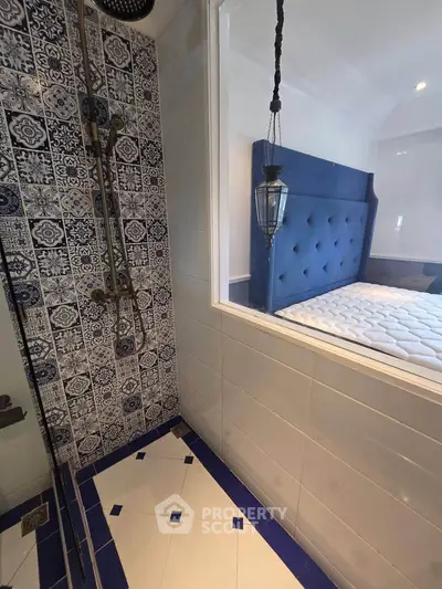 Stylish bathroom with blue patterned tiles and a view into a modern bedroom.