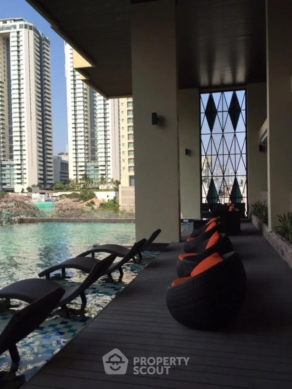 Luxurious waterfront poolside area with modern seating and stunning cityscape views.