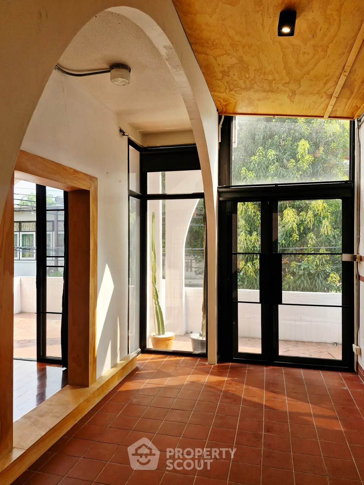 Spacious sunlit room with large windows and terracotta flooring, ideal for modern living.