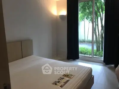 Cozy bedroom with large window overlooking lush greenery, perfect for relaxation and tranquility.