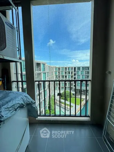 Stunning balcony view of modern apartment complex with pool and lush greenery.
