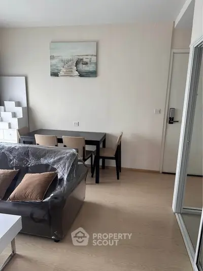 Modern living room with stylish furniture and artwork, featuring a cozy dining area and sleek flooring.