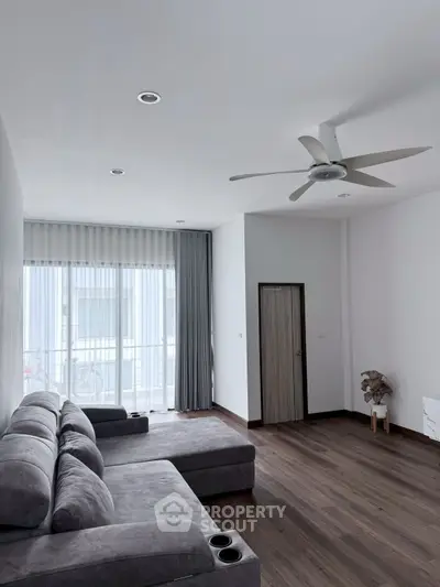Spacious modern living room with large windows and stylish gray sectional sofa.
