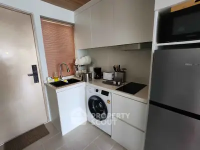 Modern compact kitchen with washing machine and sleek appliances in a stylish apartment.