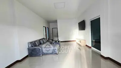Spacious modern living room with sleek furniture and large TV, perfect for relaxation.