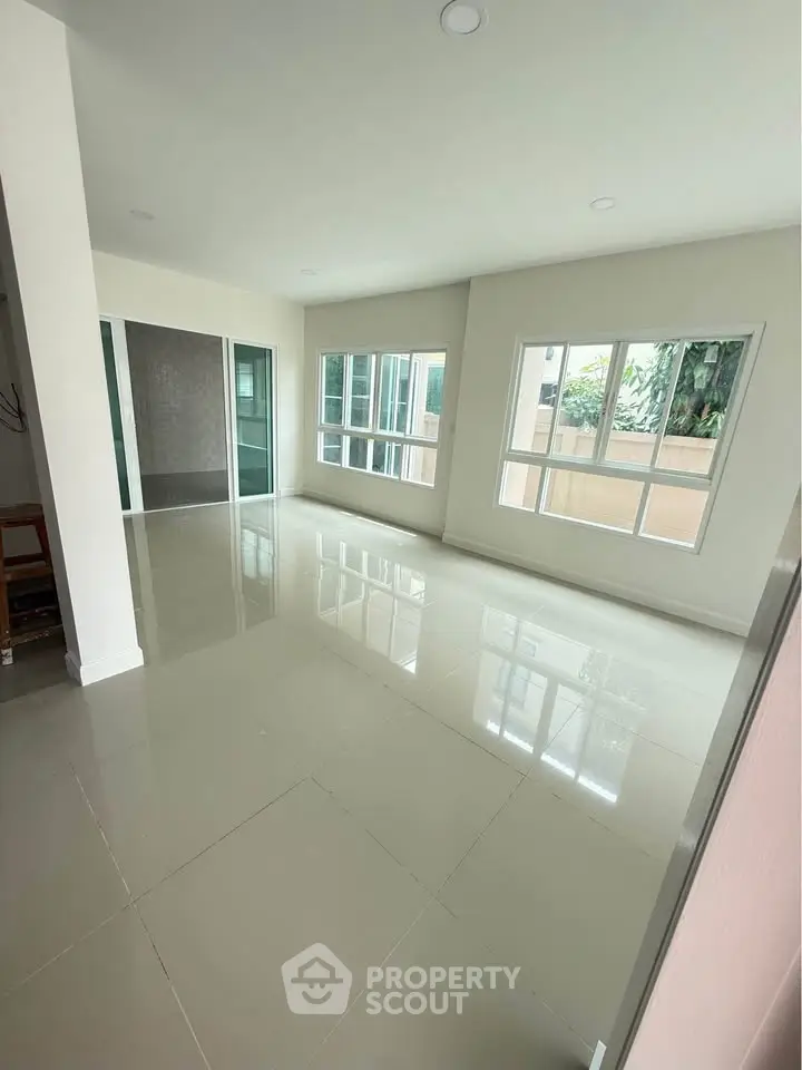 Spacious and bright living room with large windows and glossy tiled floors.