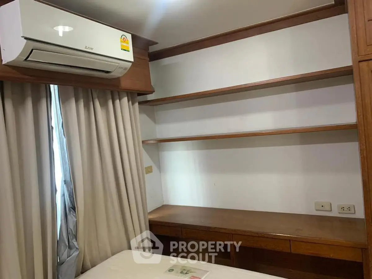 Cozy bedroom with built-in wooden shelves and air conditioning unit