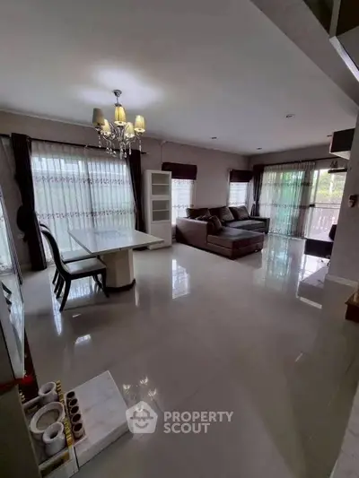 Spacious living room with elegant chandelier and large windows for natural light.