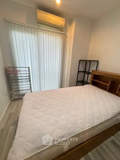 Cozy bedroom with air conditioning and natural light, featuring a comfortable bed and modern decor.