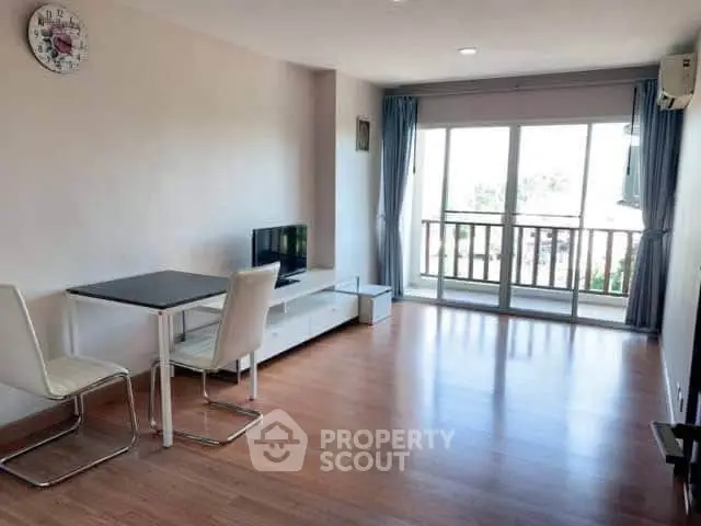 Spacious living room with wooden flooring and balcony access in modern apartment.
