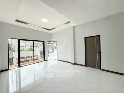 Spacious modern living room with large windows and elegant ceiling design.