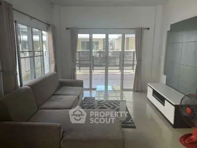 Spacious living room with modern sofa and large windows offering natural light and outdoor view.