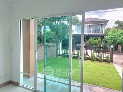 Bright living room with sliding glass doors opening to a lush garden view, perfect for indoor-outdoor living.