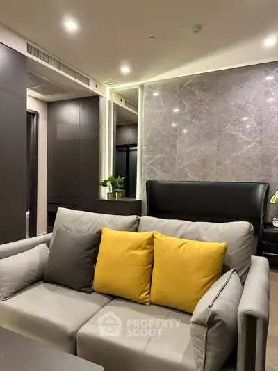 Modern living room with stylish gray sofa and yellow cushions, sleek cabinetry, and elegant lighting.