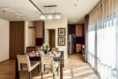 Elegant dining area with natural light, modern furniture, and open kitchen layout in a stylish apartment.