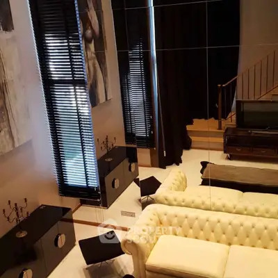 Luxurious living room with high ceilings, elegant decor, and plush seating in a modern apartment.