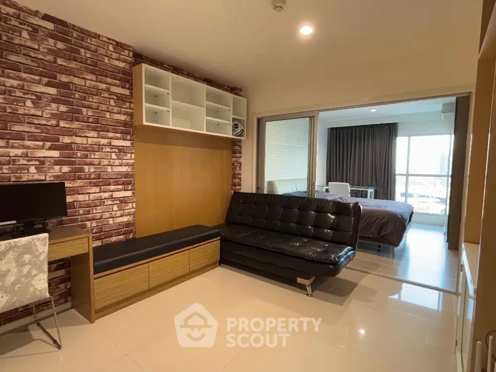 Modern studio apartment with stylish brick accent wall and sleek black leather sofa
