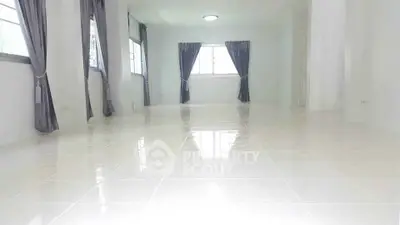 Spacious empty room with glossy tiled floor and large windows with curtains