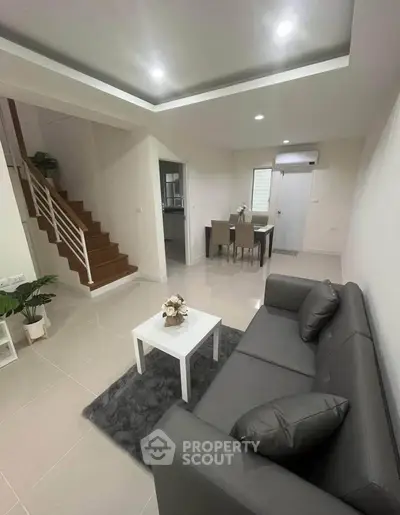 Modern living room with sleek gray sofa and elegant dining area