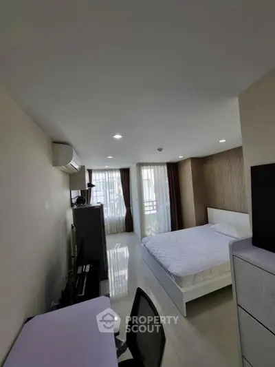 Spacious bedroom with modern furnishings and natural light in a stylish apartment.