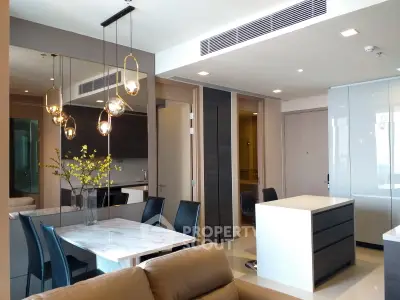 Modern open-layout living and dining area with elegant lighting and sleek furniture.