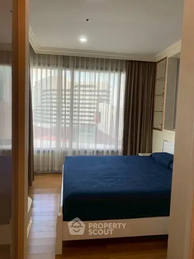 Cozy bedroom with large window and modern decor in urban apartment.