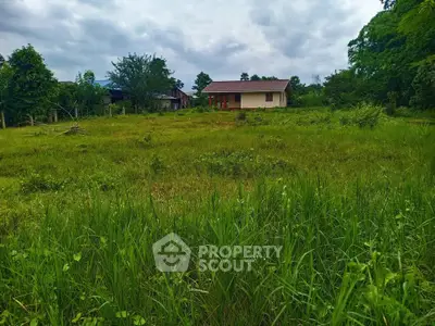 Expansive green land with a small house, perfect for development or agriculture.