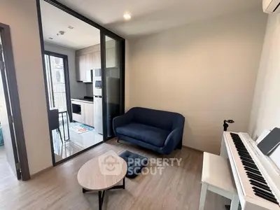Modern living room with blue sofa and piano, open kitchen layout, and stylish decor.