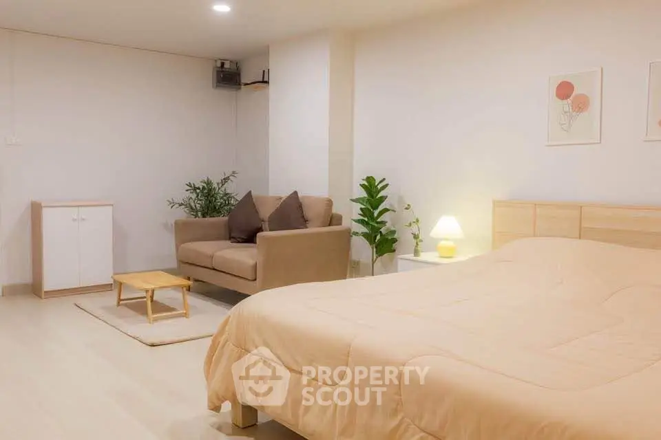 Cozy bedroom with a small sofa and modern decor, perfect for relaxation.